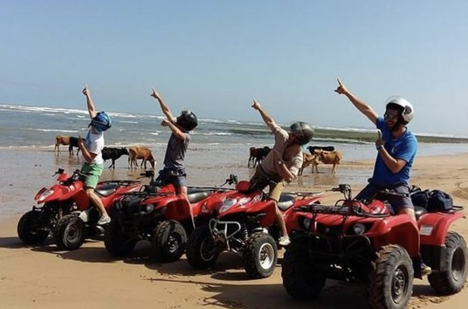 Helmeted riders on red quad bikes on the beach